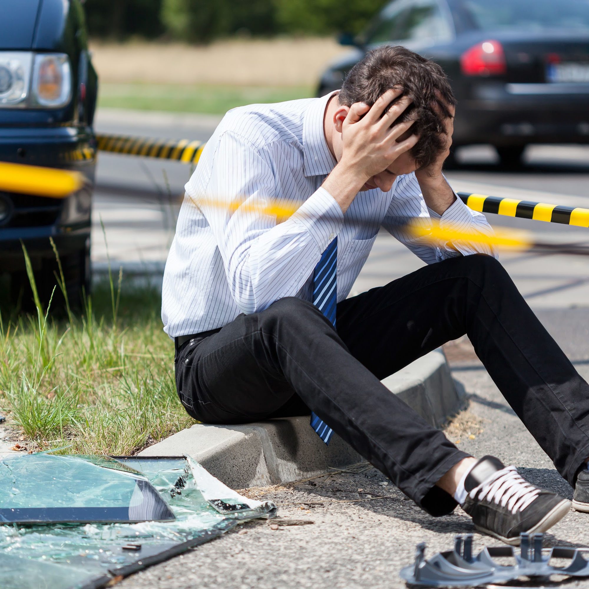 Image of a person sitting on a curb with his head in his hands after an accident wondering What are the common types of car accident lawsuits